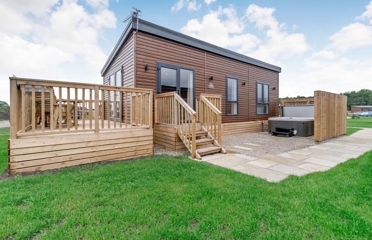 A house with a wooden deck and hot tub at Pear Tree Spa near Thirsk