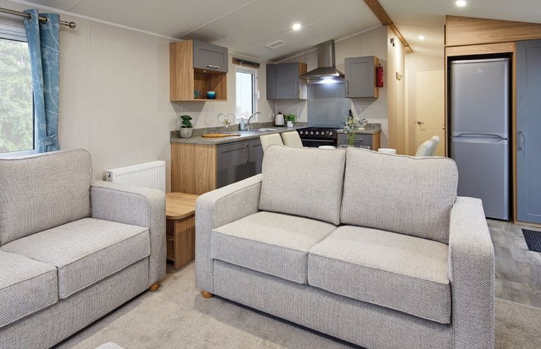A living room with sofas and a kitchen area at Banyan Waterside Spa Carlton Miniott near Thirsk
