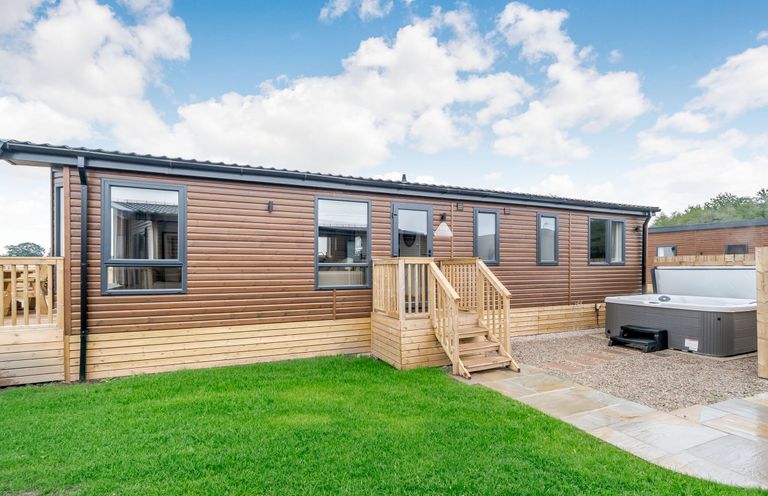A wooden cabin with steps and a hot tub at Spindle Spa Carlton Miniott near Thirsk