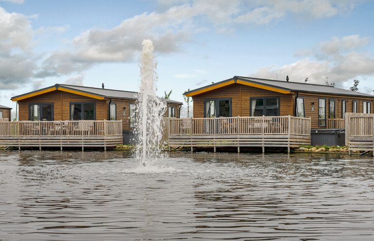 Two log cabins with decking by a lake at Oak Spa (Pet) Carlton Miniott near Thirsk