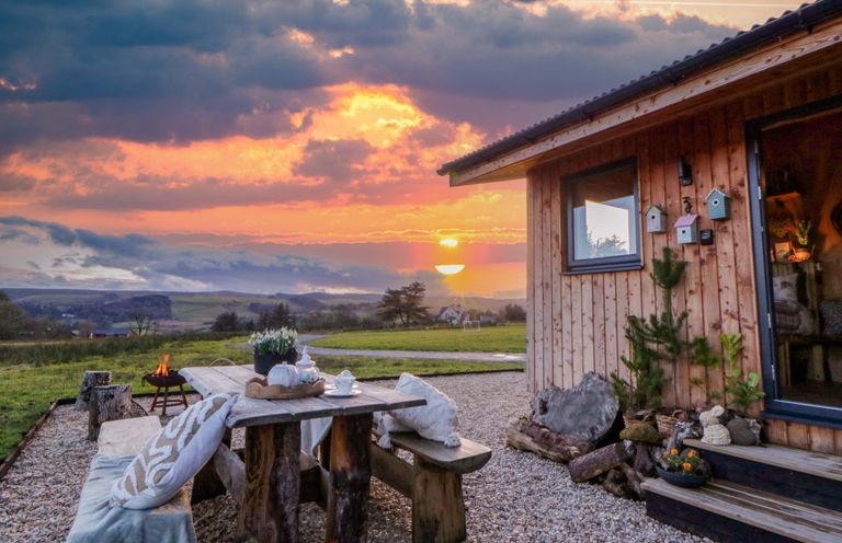 An outdoor area with a wooden table and fire pit at Harriet in Llangurig