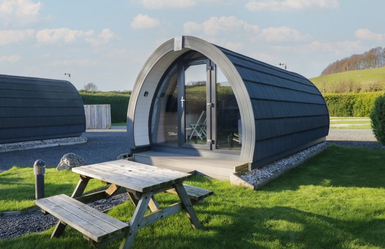 A pod with a table and benches in an outdoor area at Pod 6 (No Pets) in Tewitfield