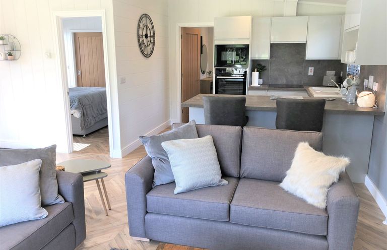 A living room with a sofa and kitchen area at Serendipity in Waltham