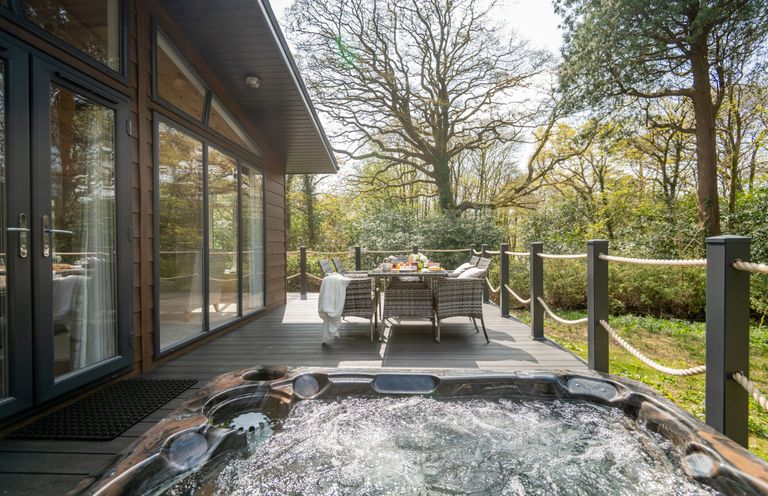 A deck with hot tub and dining area at Argel Spa in Praze-An-Beeble