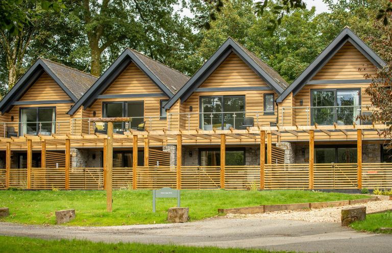 A row of wooden houses with balconies and large windows at Kilden Pet in Praze-An-Beeble