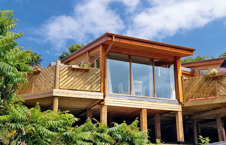 A modern building with a balcony and glass doors at Piran Spa Lodge Pet in Perranporth