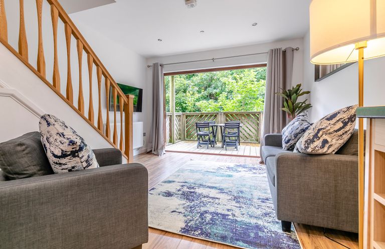 A living room with a sofa and television at Treehouse Spa in Perranporth