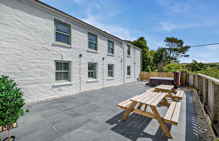 An outdoor space with picnic tables and a hot tub at The Farmhouse (Pet) in Perranporth