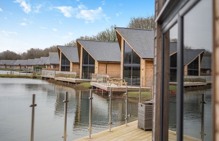 A view of wooden cabins by a lake at Tranquillity 3 (Pet) Carnforth