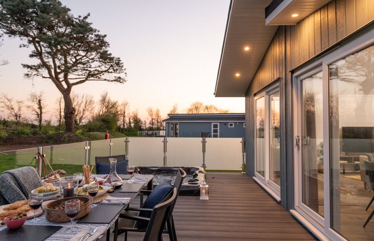 A dining setup with table and chairs on a deck at Mullion 2 Spa (Pet) Bude