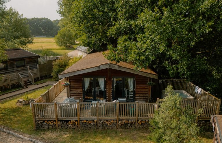 A log cabin with a deck and hot tub at Spitfire Lodge in Fair Oak