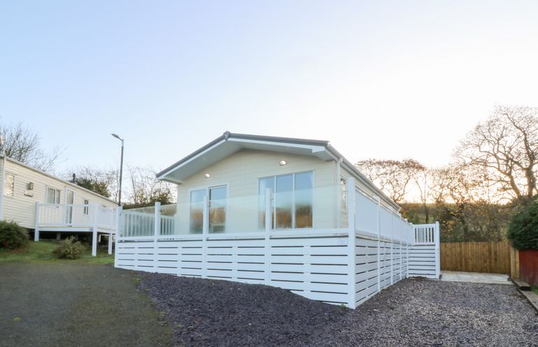 An exterior view of a lodge with a white fence at Beechwood Lodge