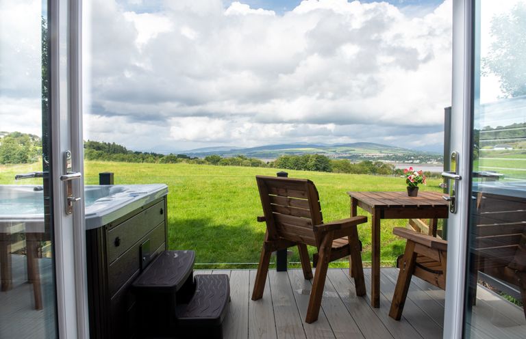 An outdoor seating area with a hot tub and table at Nethermill Lodges in Port Glasgow