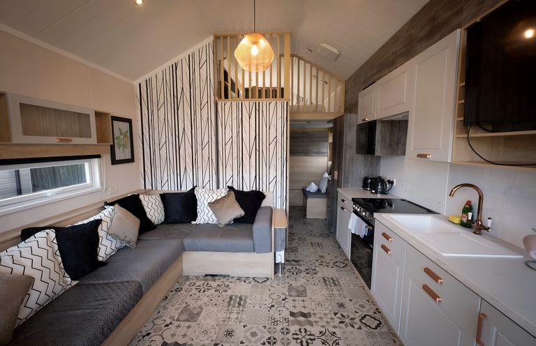 A living room with a sofa and kitchen area at Inverness Lodge in Inverness