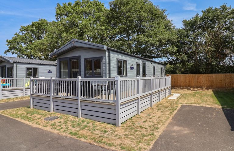 A mobile home with a deck and fence at The Oaks 2 Bedrooms Delamere