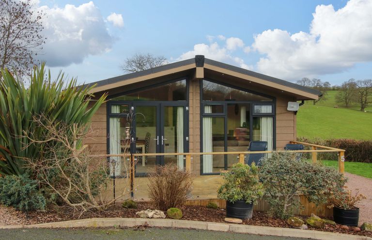 A lodge with a wooden deck and plants at 5 Hillview Lodges in Cleobury Mortimer