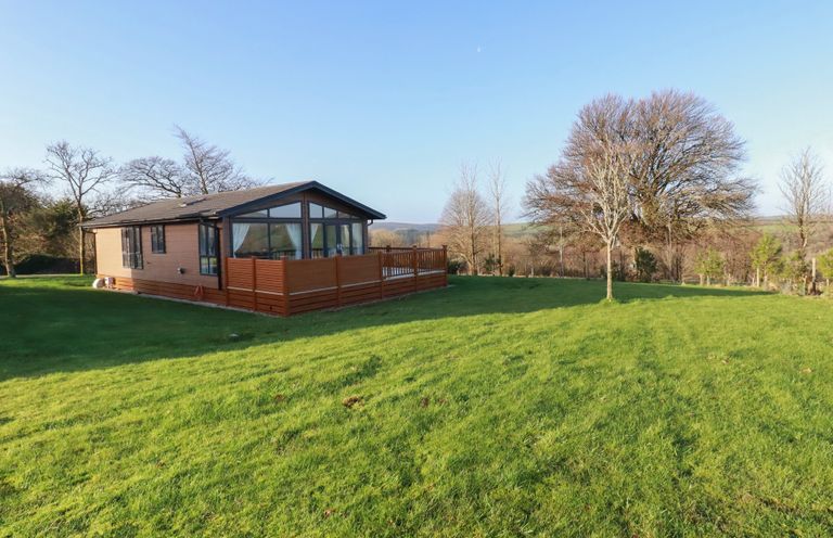 A house with a deck on a lawn at Moorland View