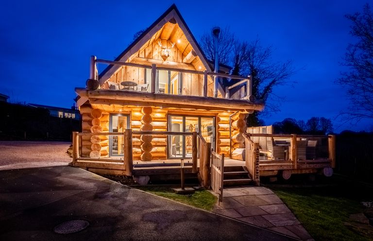 A log cabin with a deck and lighting at Keepers Cabin Addingham
