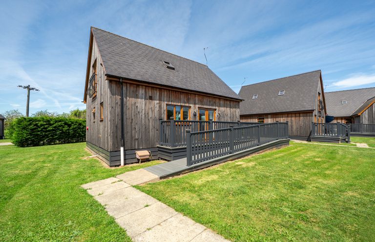 A wooden house with a deck and grass area at James Ville Marina Lodge 7 Brigg