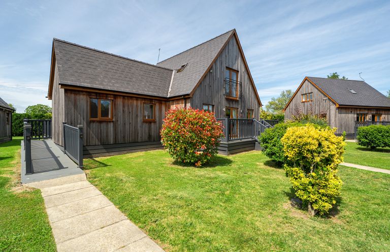 A wooden house with a balcony and garden at James Ville Marina Lodge 9 Brigg