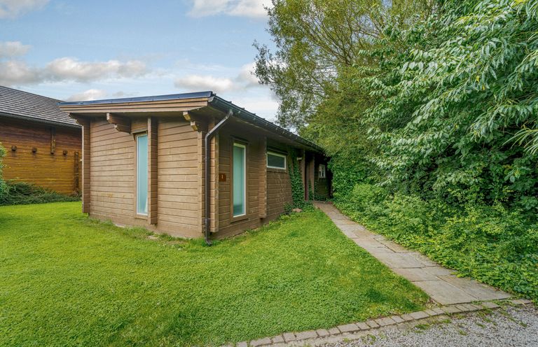 A wooden building with windows and a pathway at Poplar Lodge (Pet) Thirsk
