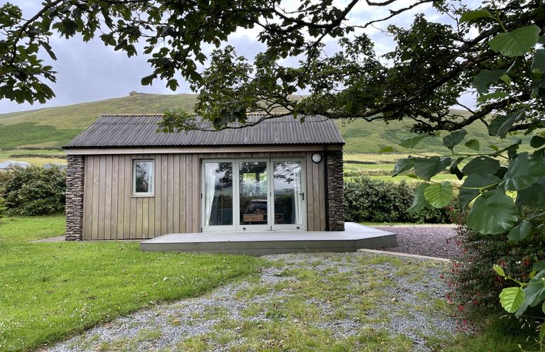 A cabin with a stone wall and sliding door at The Faithfuls Cabin in Dingle, County Kerry