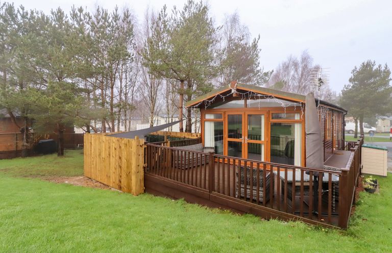 An outdoor view of a cabin with a deck at Harper's Hideaway near Felmoor Holiday Park near Felton