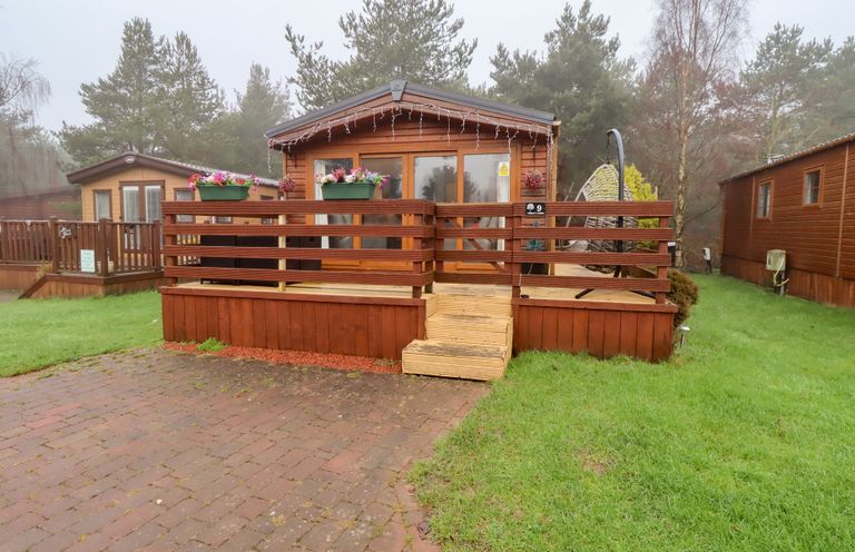A log cabin with wooden deck and steps at Chloe's Cabin near Felmoor Holiday Park near Felton