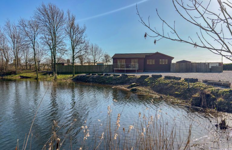 A water body with a building and trees at Star Carr Lakes
