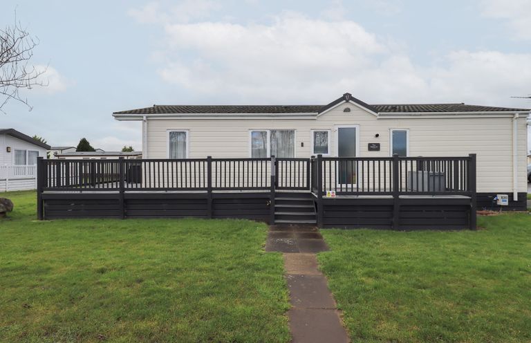 A modular home with a deck and grass area at Lily's Lodge in Morecambe