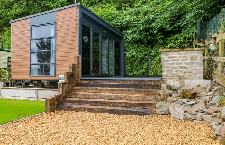 An outdoor view of a modern building with steps and gravel at The Pod in Ferryside