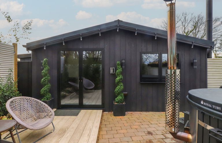 An outdoor area with a hot tub and seating at Caban Tan Y Ffawydd in Chwilog near Y Ffor