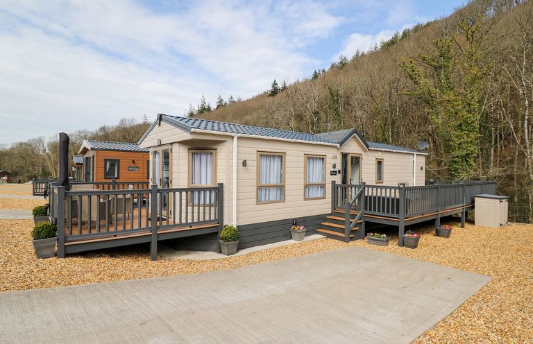 A mobile home with a deck and steps at 33 Woodpecker Lodge in Llanarth