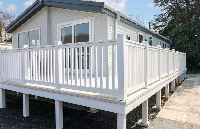 An exterior view of a house with a deck and railing at Dukes Meadow in Carmarthen
