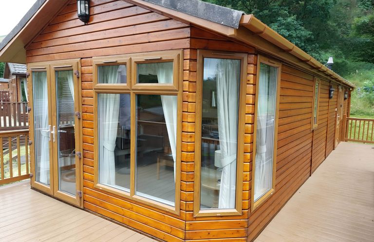 An exterior view of a log cabin with a deck and large windows at 2 Bed Lodge-Sleeps 4-stunning views -Pet Friendly, Troutbeck