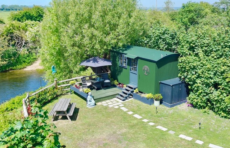 A garden with a shepherd's hut, seating area, and plants at Salthaven Shepherds Hut Pevensey Bay