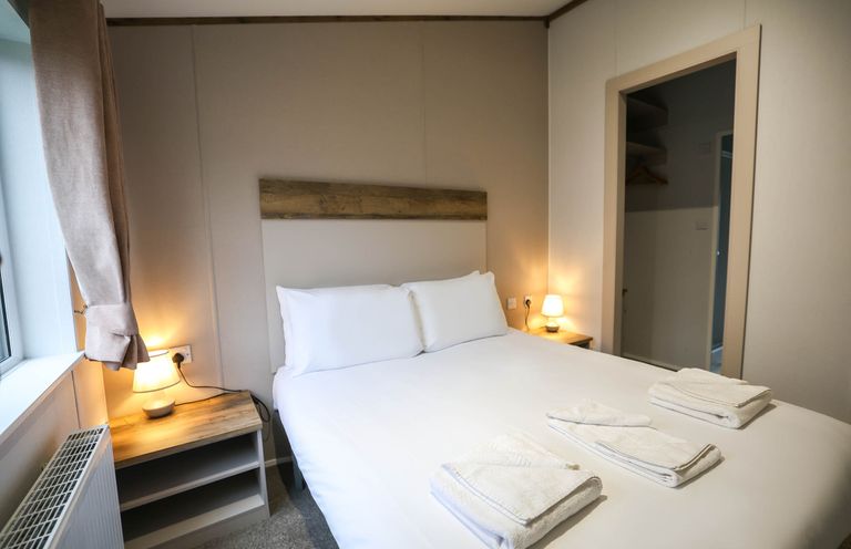 A bedroom with a bed and bedside table at Laurel Waterside Spa Carlton Miniott near Thirsk