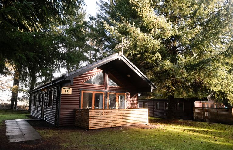 A log cabin with a deck in the woods at Sidlaw in Fowlis near Dundee