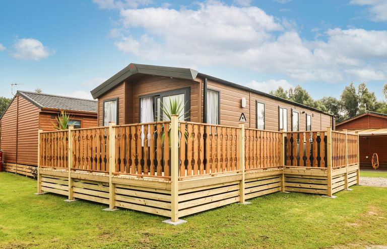 A caravan with a wooden deck at Hedgehog Lodge in Carnforth
