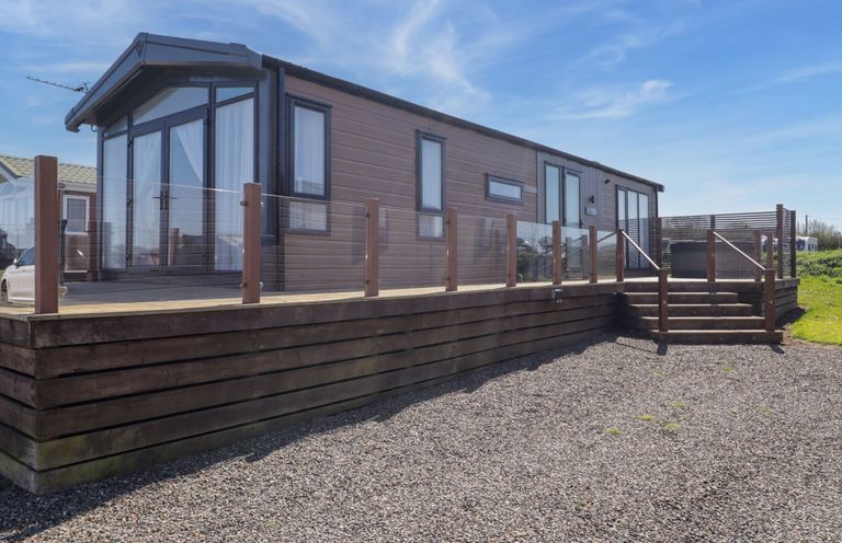 A mobile home with a deck and steps at Stone Crab Lodge in Haverfordwest