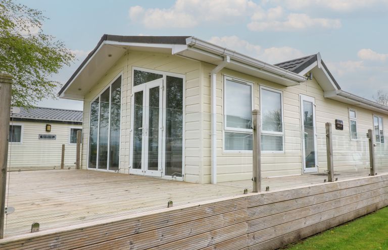 A house with a deck and multiple windows at Plot 34 Carlisle