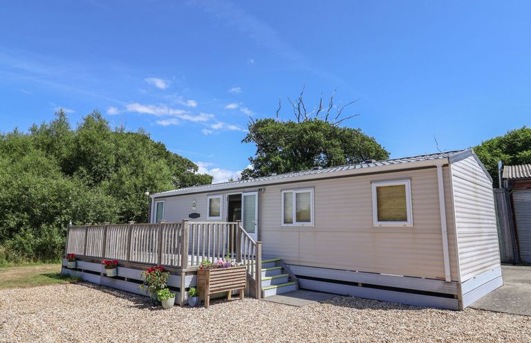 A mobile home with a deck and steps at The Hideaway in Portesham