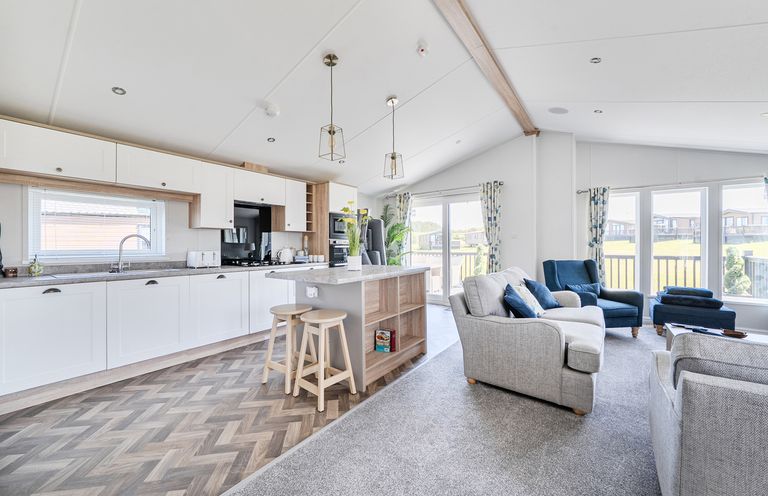 A kitchen with bar stools and living area at Atlantic Breeze Luxury Lodge sleep 6 Mullacott near Ilfracombe