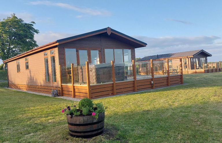 An outdoor view of lodges with decking and garden at 2 Bedroom Sleeps 4 Lodge Smart Tv Hot tub Dogs Ok near Lochwinnoch