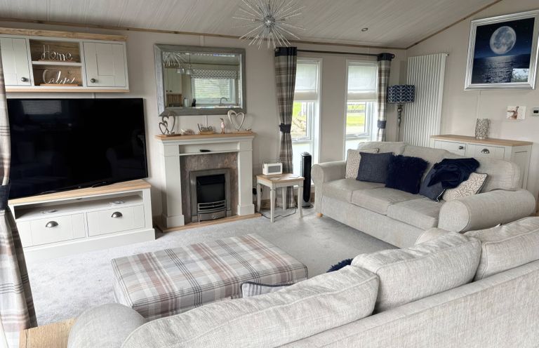 A living room with a television and fireplace at Harrogate Lodge Sleeps4 South Facing Decking Lufflands Caravan Park near Holsworthy
