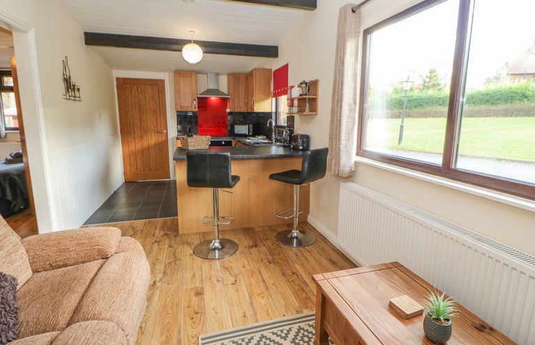 A kitchen and living area with stools a sofa and a window at Bluebell Lodge in Saltburn-by-the-Sea