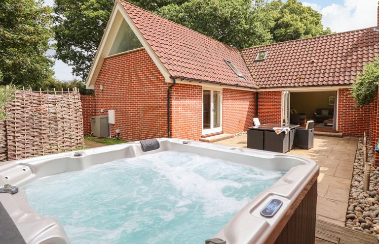An outdoor patio area with a hot tub dining table and chairs at Oak Tree Lodge in Crostwick near Norwich