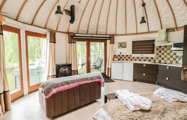 A circular living space with a sofa table kitchenette and bed at Island Yurt in Beckford near Tewkesbury