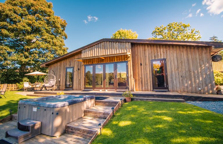 An outdoor area with a hot tub and seating at Sycamore Lodge Nantmel near Rhayader