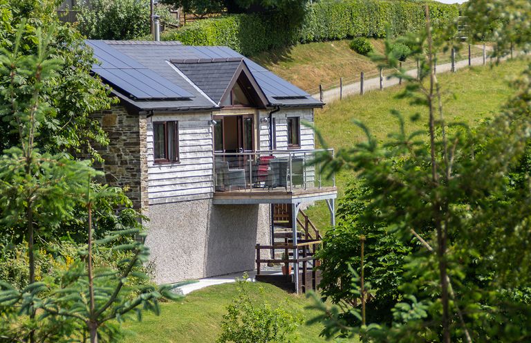 A small house with solar panels and a balcony on a grassy hillside at Black Mountain View in Llanafan Fawr near Builth Wells